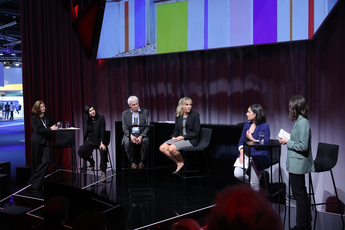 Vier Personen bei einer Podiumsdiskussion. Vier Personen bei einer Podiumsdiskussion.