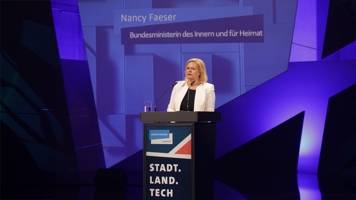 Nancy Faeser, Bundesministerin des Innern und für Heimat steht auf der SCCON-Bühne hinter einem Rednerpult, blauer Hintergrund. Nancy Faeser, Bundesministerin des Innern und für Heimat steht auf der SCCON-Bühne hinter einem Rednerpult, blauer Hintergrund.