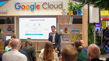 Der Messestand von Google Cloud auf der SCCON 2023 – im Vordergrund Menschen, die dem Vortrag eines Experten von Google zuhören